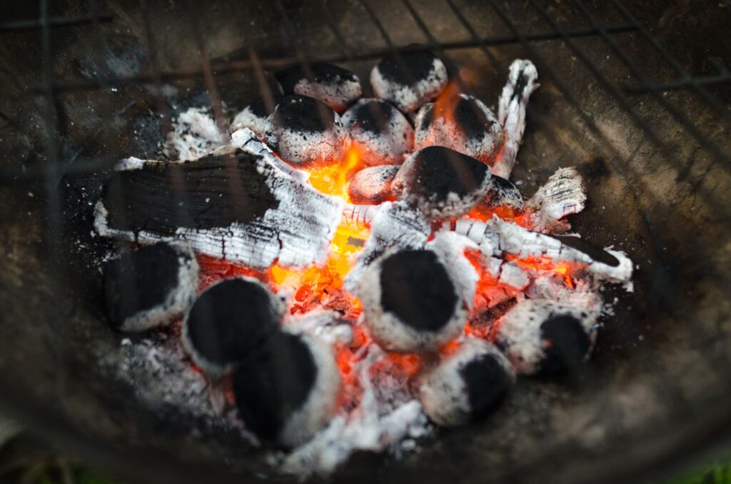 Close-up of glowing charcoal briquettes in a barbecue, ready for grilling.